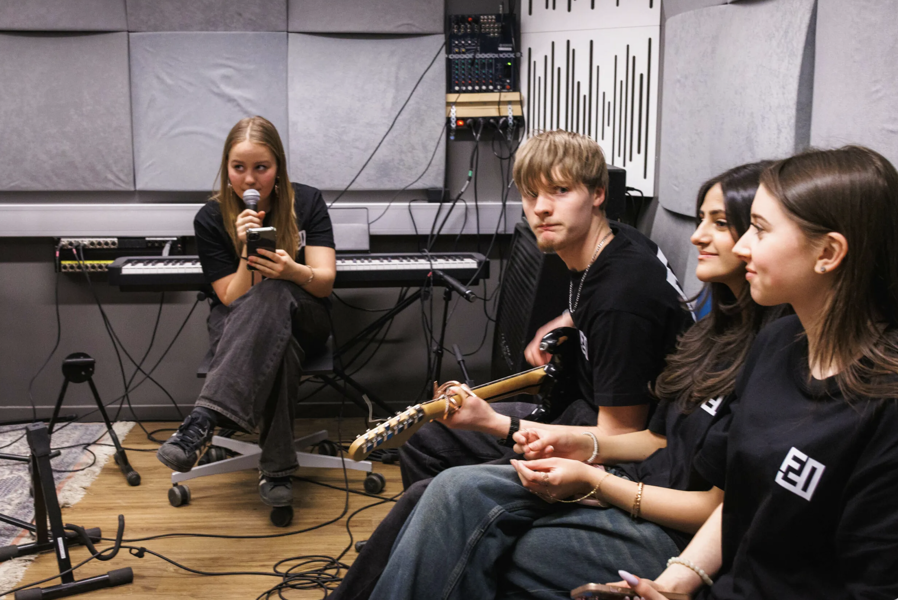 En gruppe mennesker som sitter på en scene med mikrofoner