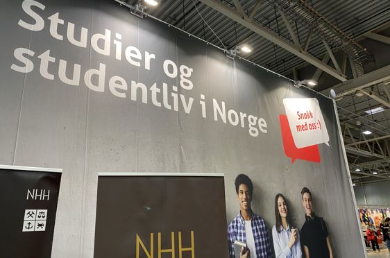 en gruppe mennesker som står foran et stort skilt