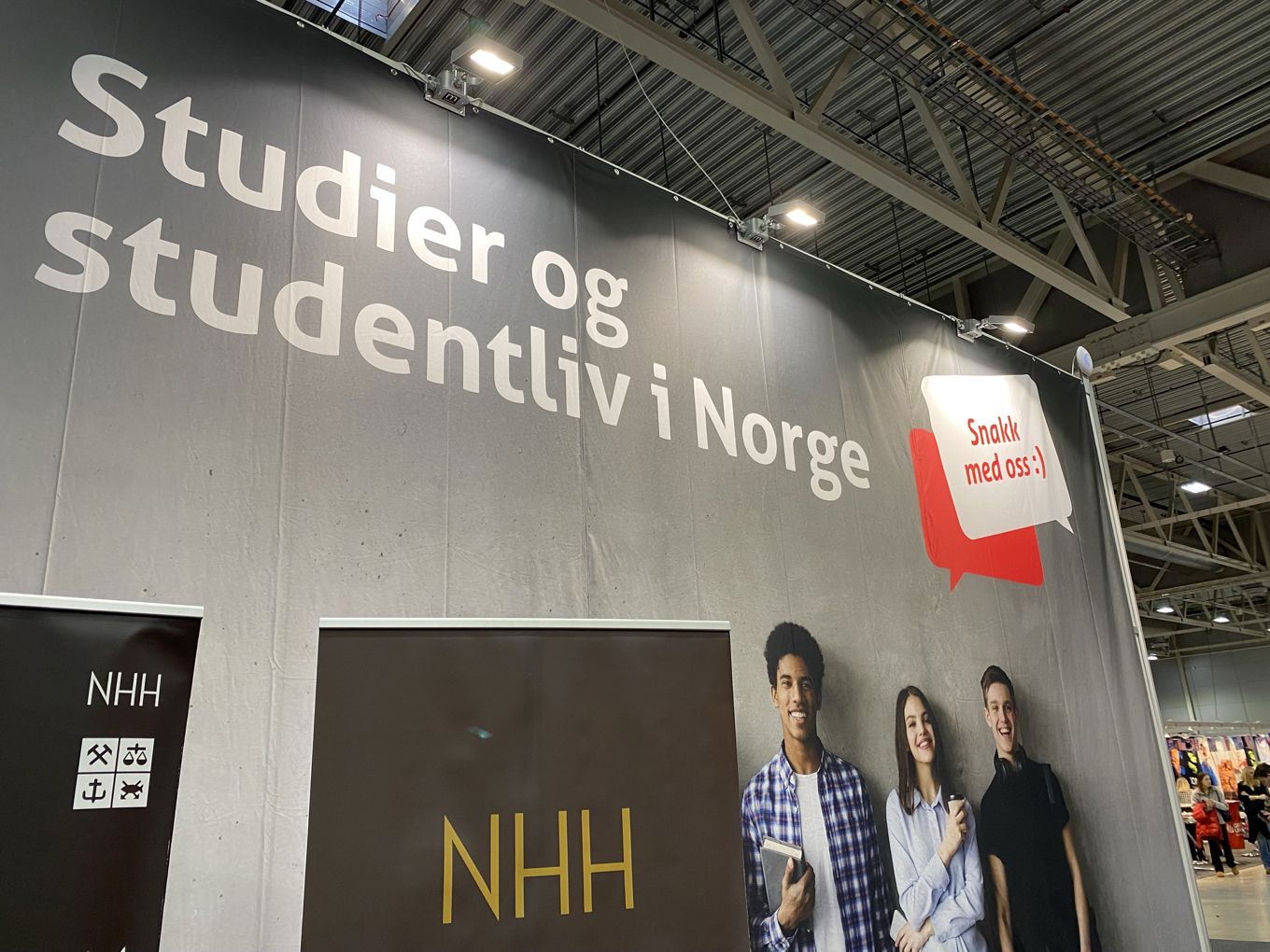 en gruppe mennesker som står foran et stort skilt en gruppe mennesker som står foran et stort skilt