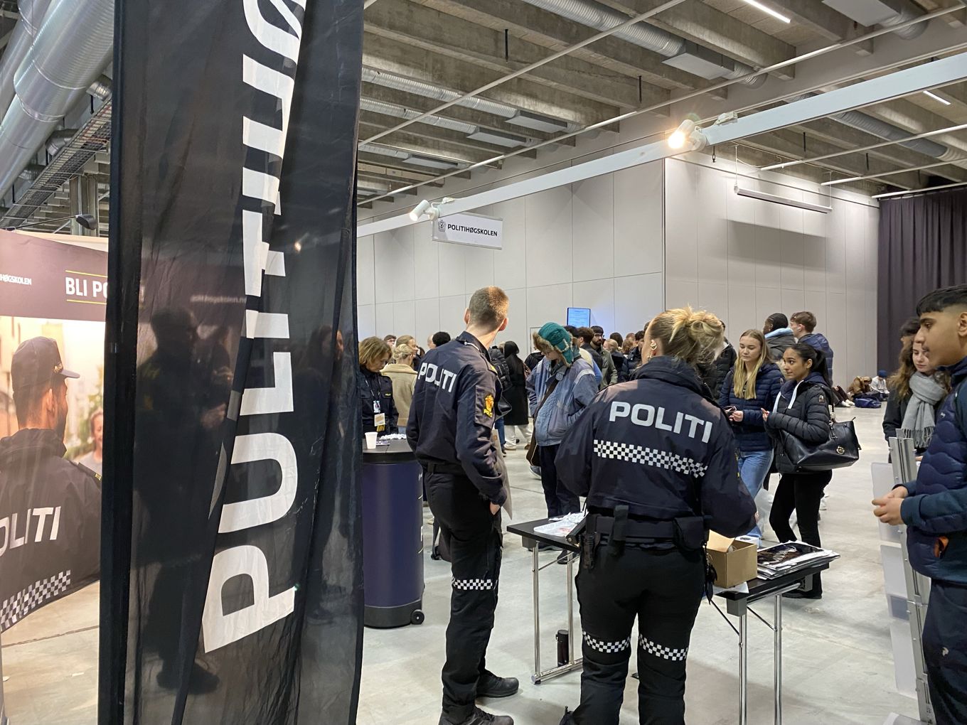 en gruppe mennesker som står i et rom med et skilt en gruppe mennesker som står i et rom med et skilt