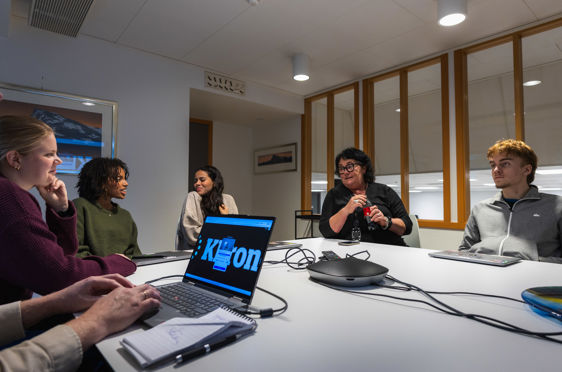 en gruppe mennesker som sitter rundt et bord med en bærbar PC
