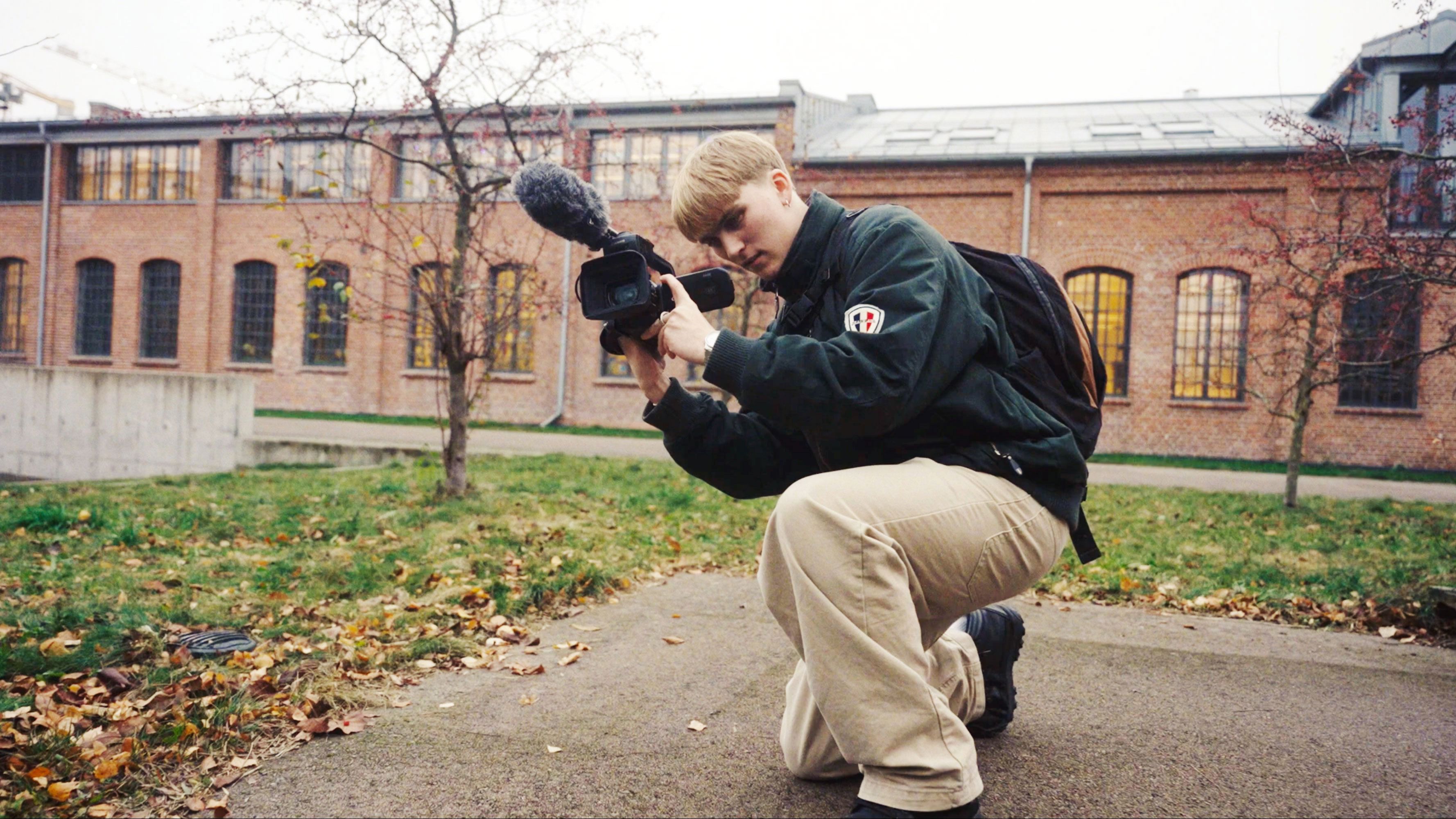 en person som kneler på bakken og holder et kamera