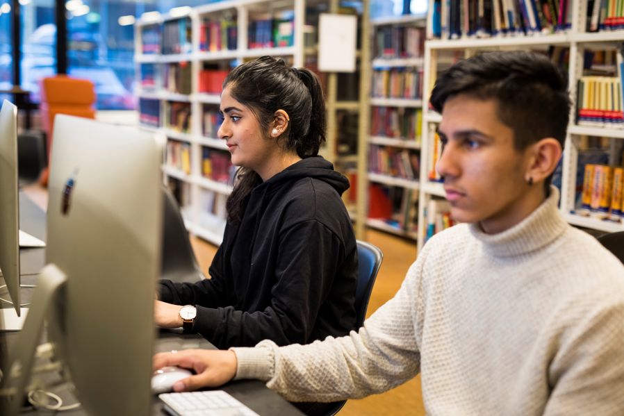 Elever jobber på Mac i skolebiblioteket foto Kristine Lindebøe