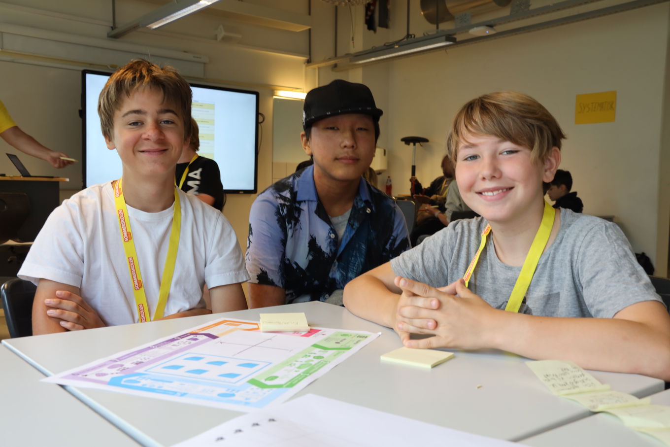 en gruppe barner som sitter ved et bord med et papir;